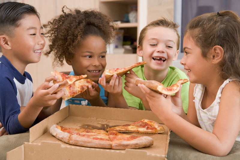 4 young children eating pizza together